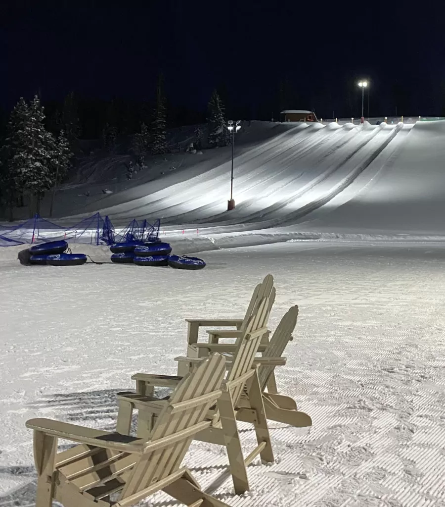 Ski slope with a set of tubes in the background and a chair closer in frame